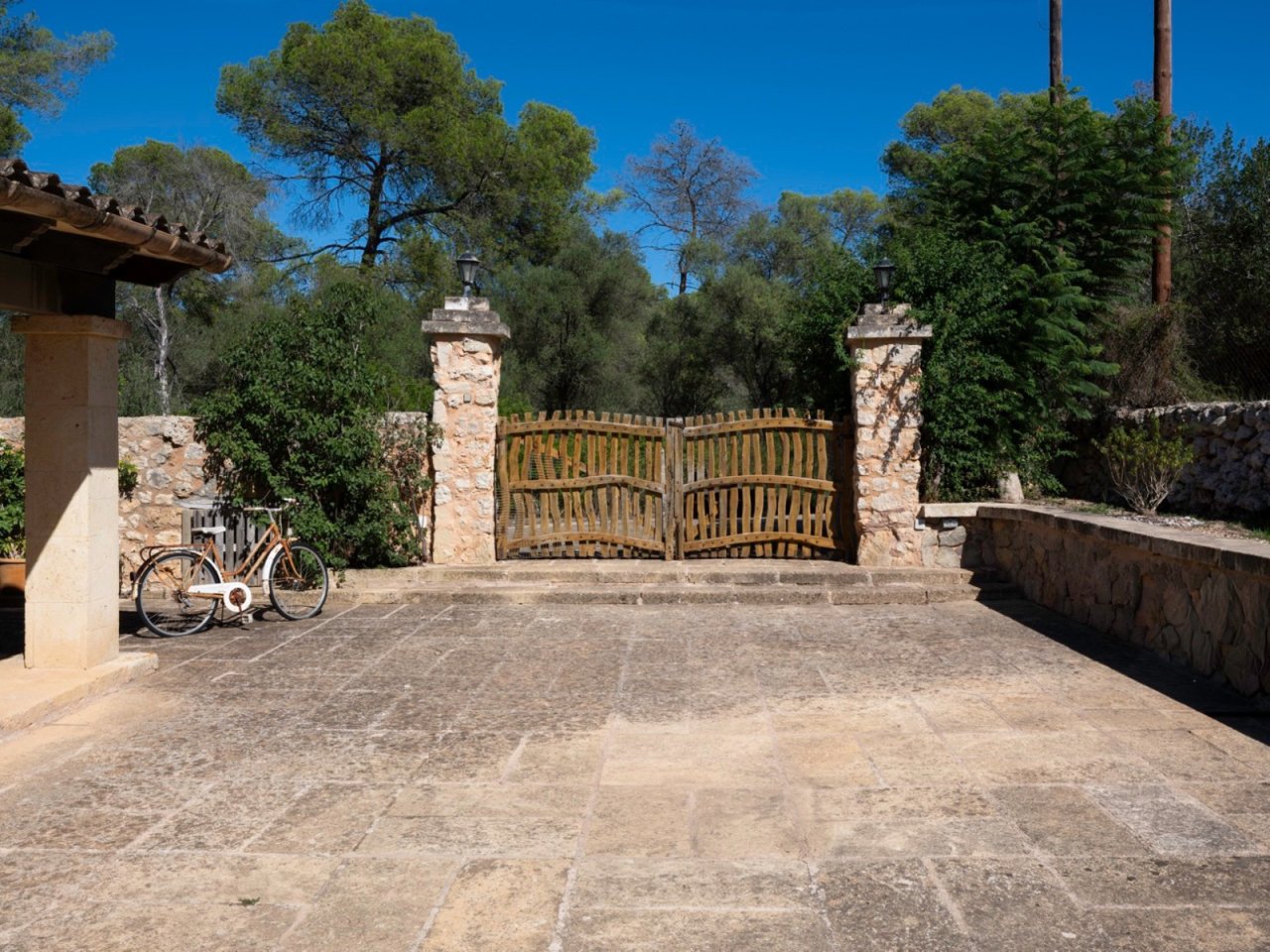 Imponente puerta de entrada con pilares de piedra natural macizos y hojas de madera rústica