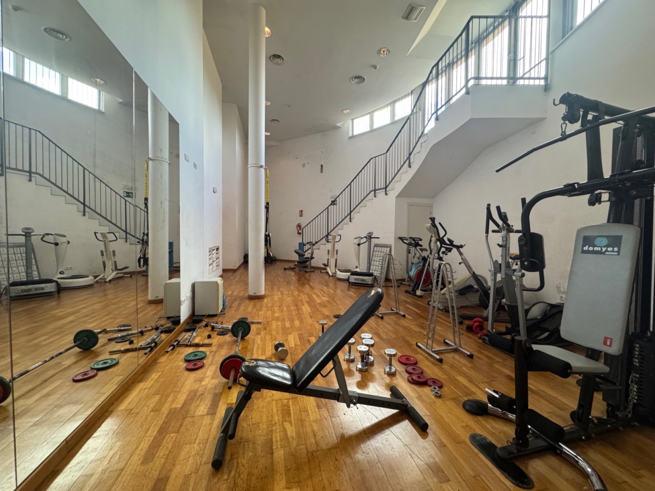 Gimnasio moderno con paredes de espejos, tragaluces y distribución inteligente del espacio