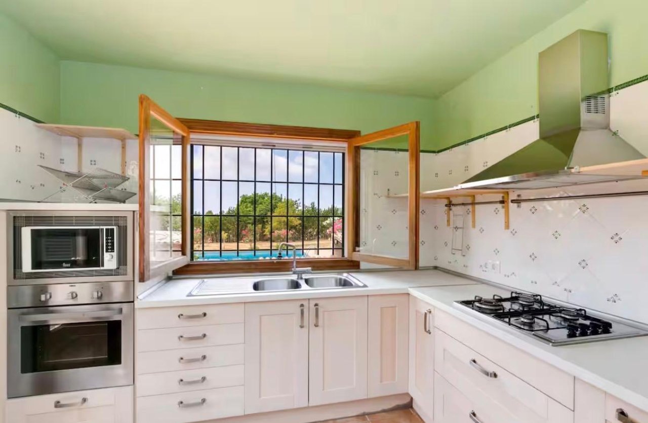 Cocina moderna con grandes ventanas de madera y equipamiento de alta calidad