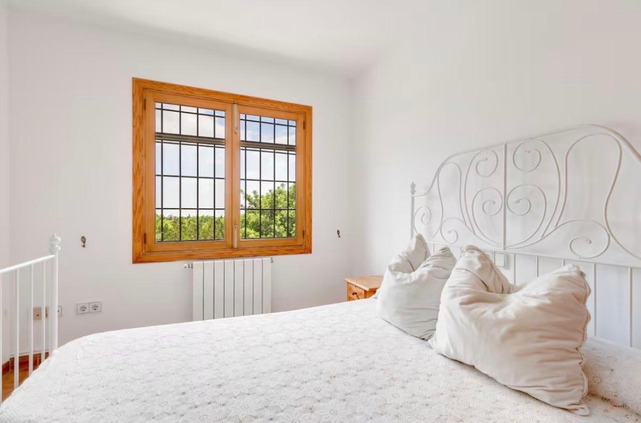 Dormitorio luminoso con ventanas de madera de gran tamaño y radiador