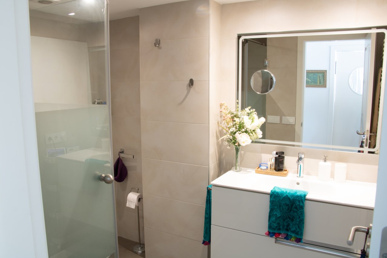 Baño moderno con ducha a ras de suelo y espejos iluminados Baño moderno con ducha a ras de suelo y espejos iluminados