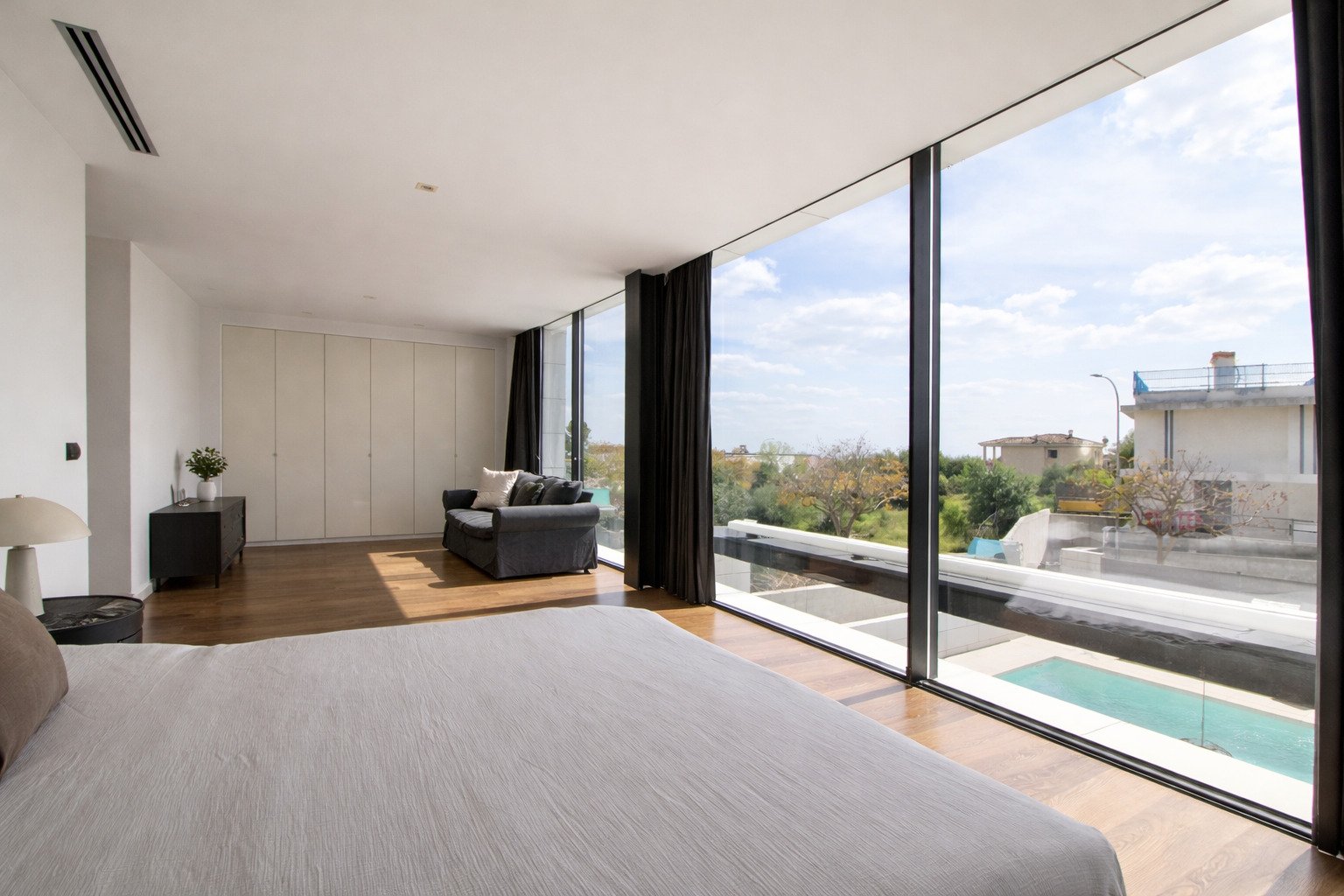 Habitación principal con paredes de vidrio correderas de suelo a techo y vista a la piscina Habitación principal con paredes de vidrio correderas de suelo a techo y vista a la piscina