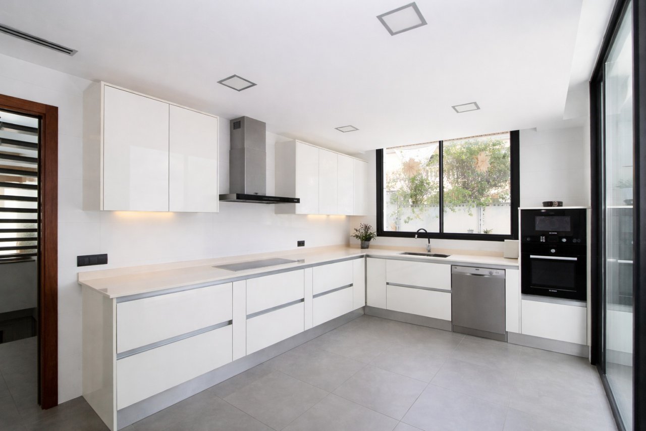 Cocina moderna en forma de L con electrodomésticos empotrados de alta calidad y entrada de luz natural Cocina moderna en forma de L con electrodomésticos empotrados de alta calidad y entrada de luz natural
