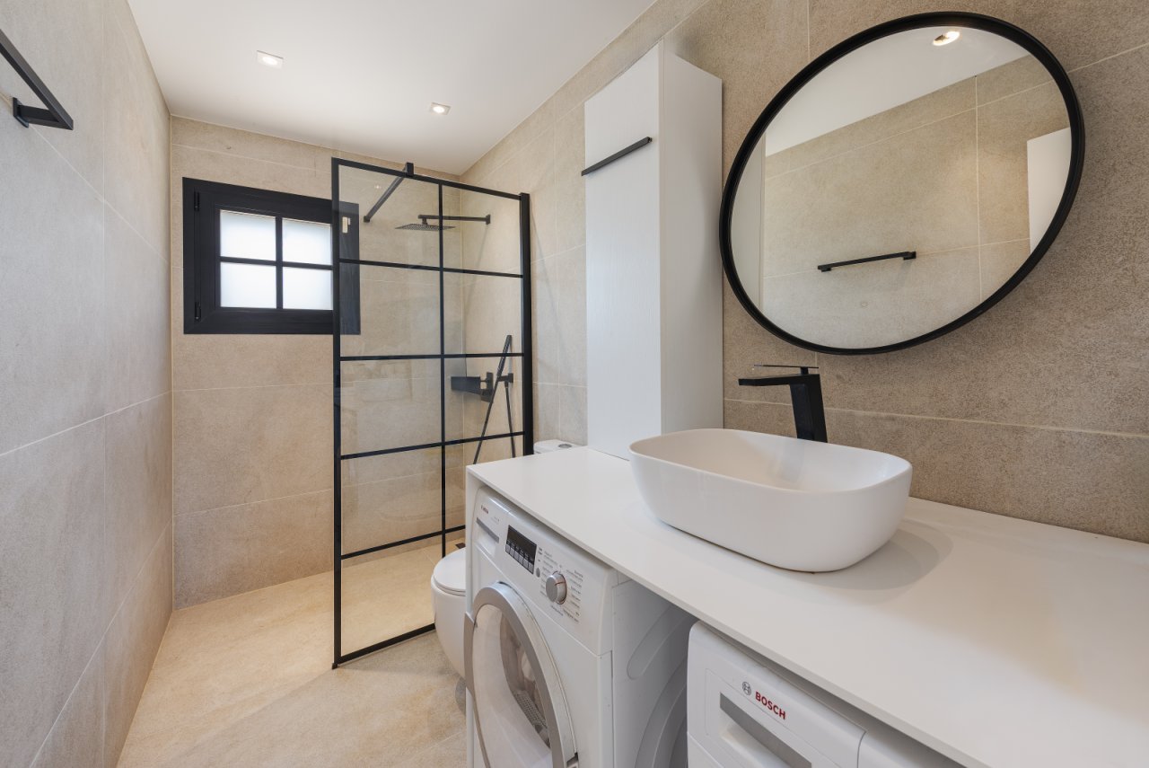 Baño moderno con ducha a ras de suelo, lavabo y práctica integración de la lavadora