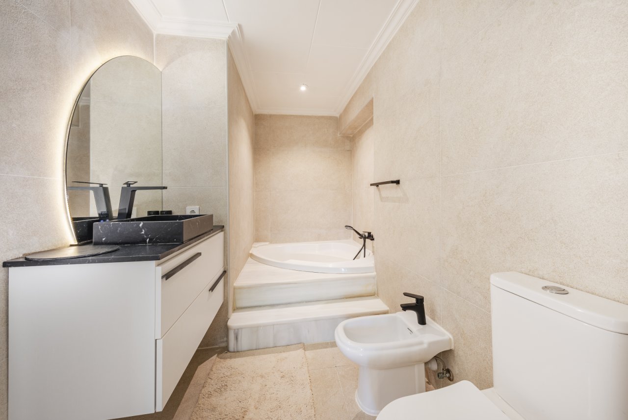 Baño moderno con bañera independiente, doble lavabo y zona de ducha accesible