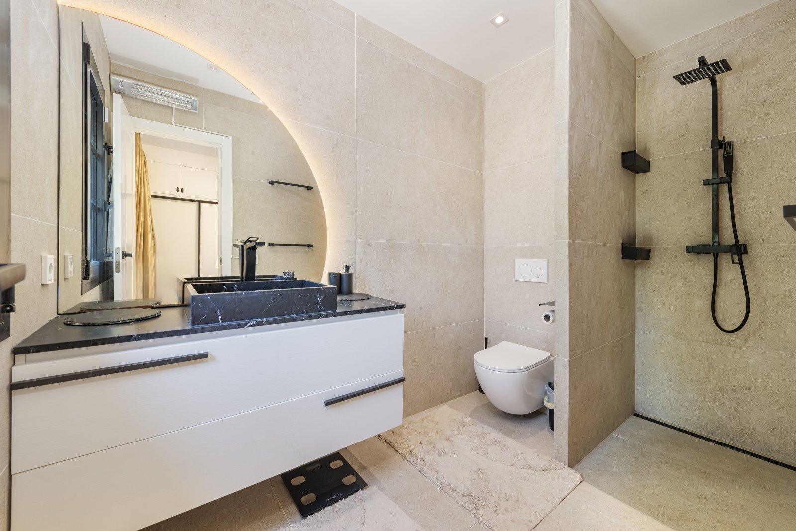 Baño moderno con ducha a ras de suelo, lavabo de mármol y distribución inteligente del espacio
