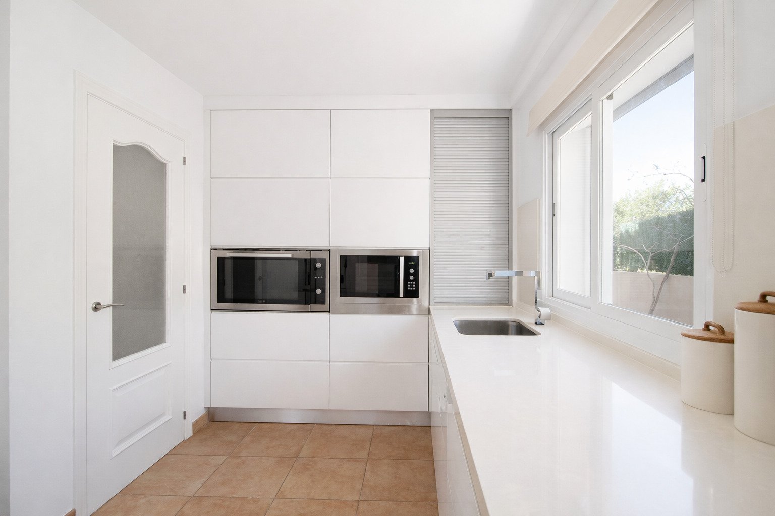 Cocina moderna con equipamiento integrado y acceso directo a la terraza