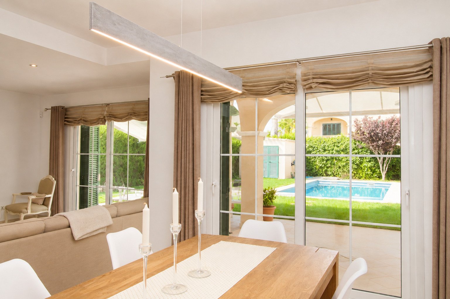 Área de comedor con puertas correderas de vidrio de gran tamaño y iluminación LED integrada en el techo Área de comedor con puertas correderas de vidrio de gran tamaño y iluminación LED integrada en el techo