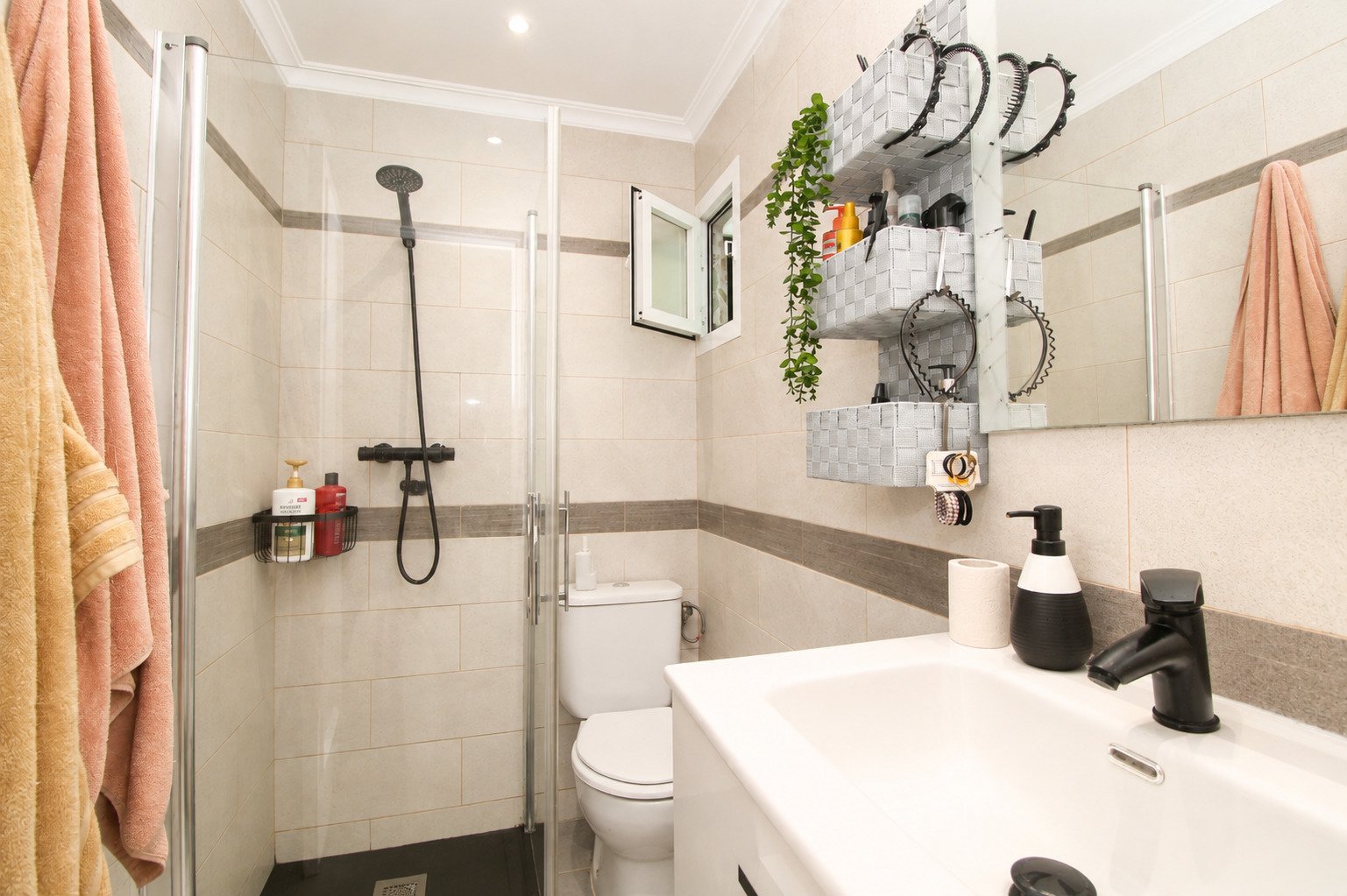 Baño moderno con ducha a nivel del suelo y organización inteligente en la pared