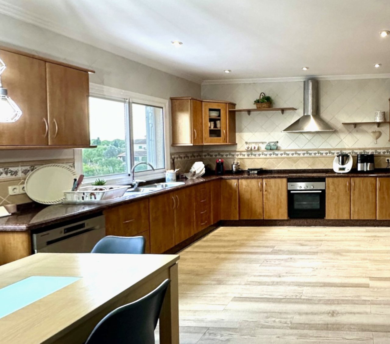 Cocina moderna con forma en L funcional, electrodomésticos empotrados de alta calidad y ventanas de gran tamaño Cocina moderna con forma en L funcional, electrodomésticos empotrados de alta calidad y ventanas de gran tamaño