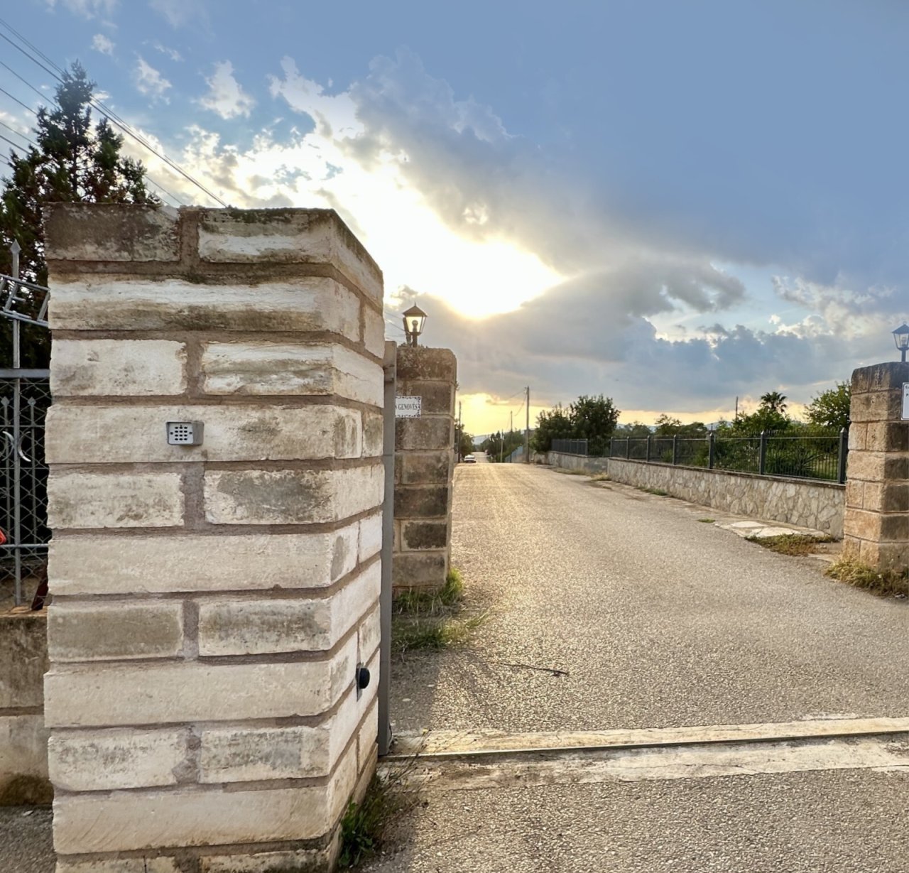 Entrada representativa con pilares de piedra natural macizos y acceso pavimentado Entrada representativa con pilares de piedra natural macizos y acceso pavimentado