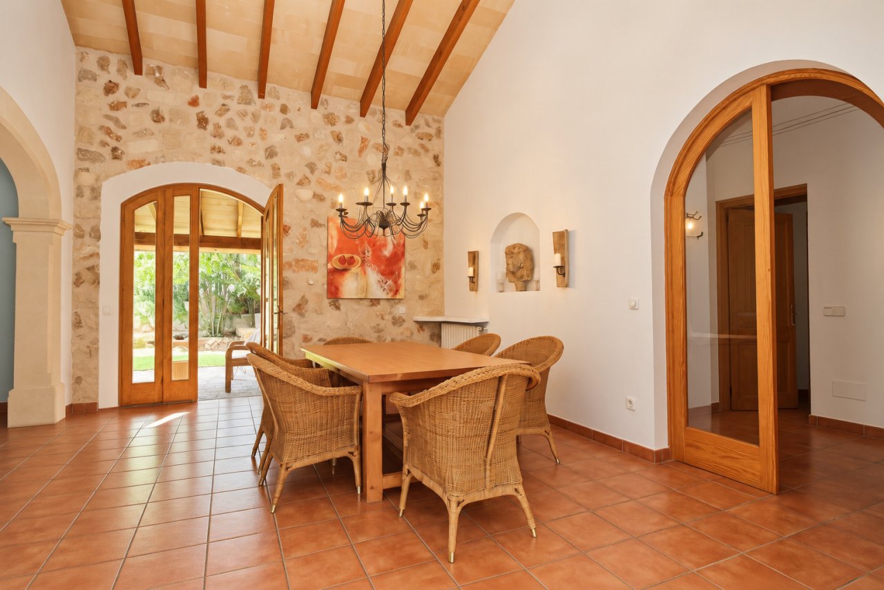 Comedor con pared de piedra natural, techo con vigas de madera y elegantes arcos redondos