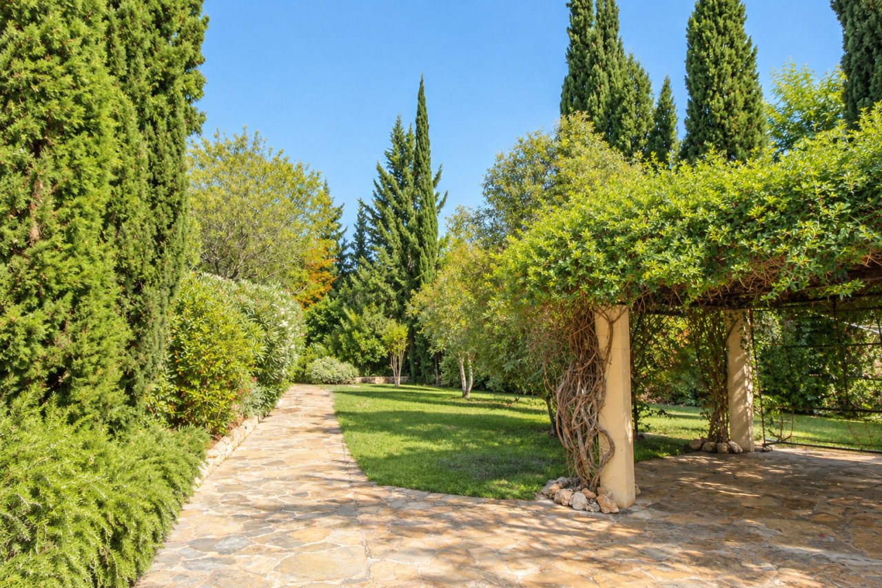 Jardín privado similar a un parque con elegante pérgola y senderos empedrados