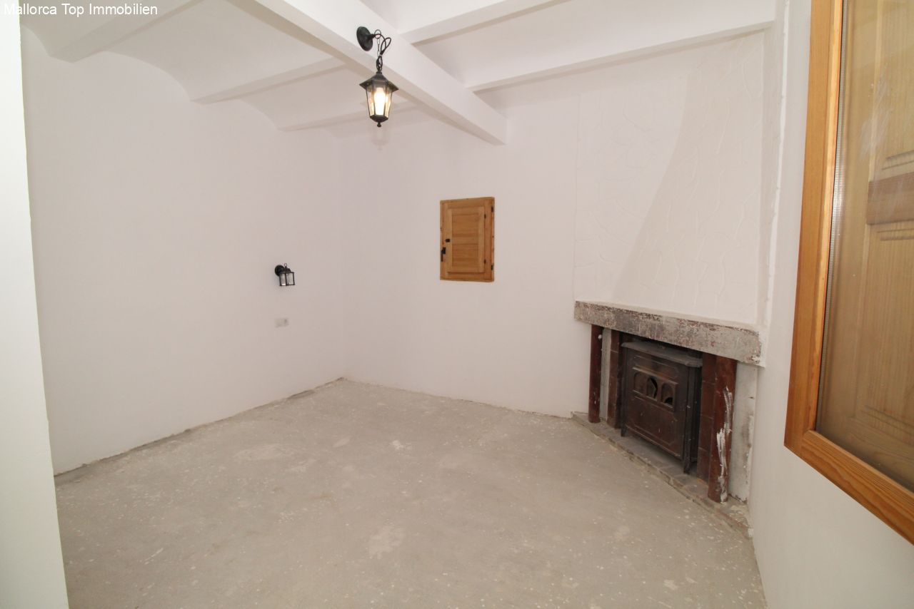 Espacio habitable con una estufa de leña con carácter y una estructura de techos altos, ideal como base para una renovación personalizada.