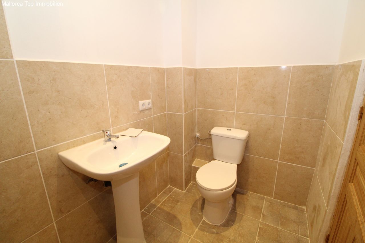 Baño de invitados funcional con estándar sanitario moderno: equipamiento práctico y superficies de azulejos de fácil mantenimiento