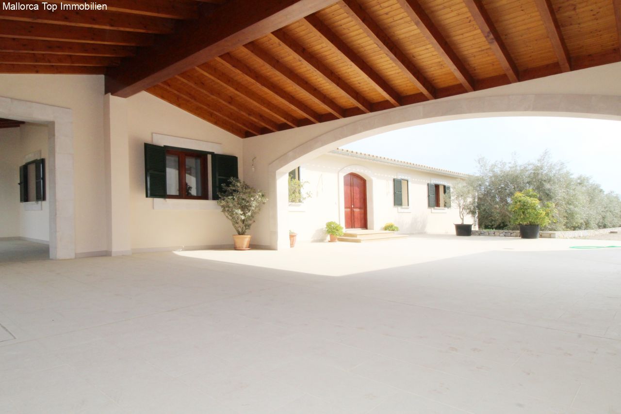 Terraza cubierta con techo de vigas de madera con carácter y conexión abierta a la casa principal