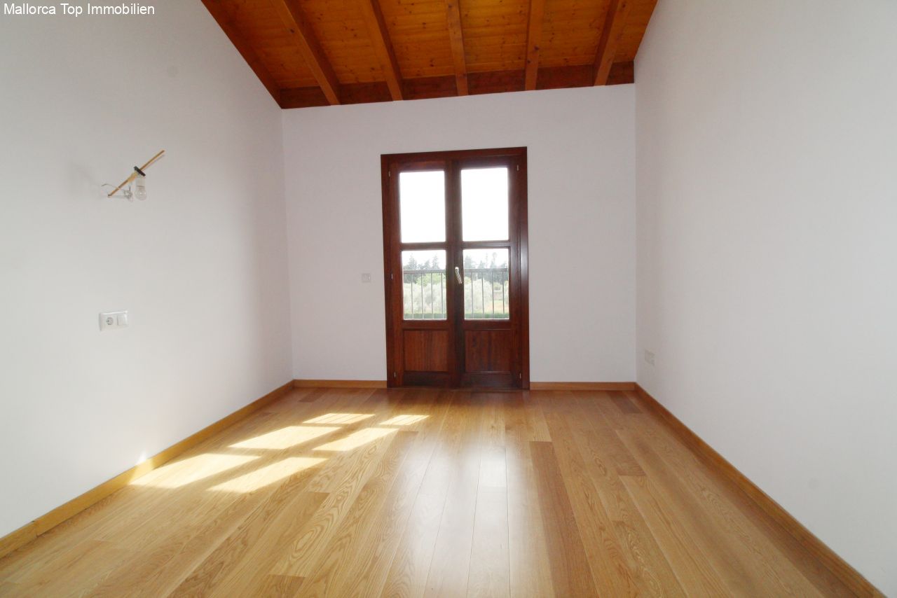 Habitación luminosa con techo de vigas de madera y puertas francesas de cristal al exterior