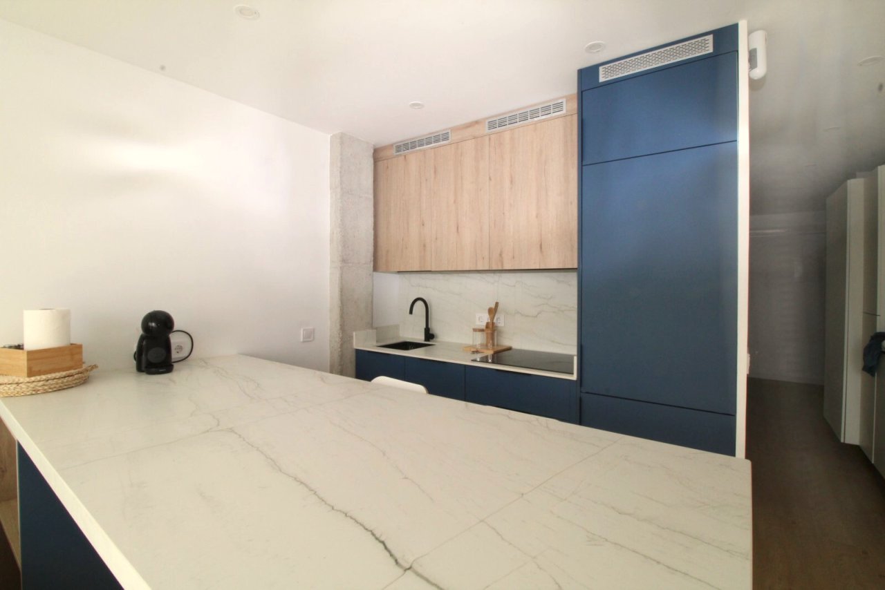Línea de cocina moderna con barra integrada y equipamiento de alta calidad
