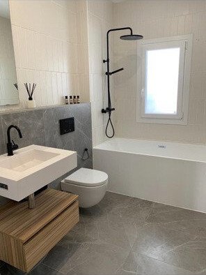 Baño moderno con ducha a ras de suelo, bañera y equipamiento sanitario de alta calidad Baño moderno con ducha a ras de suelo, bañera y equipamiento sanitario de alta calidad