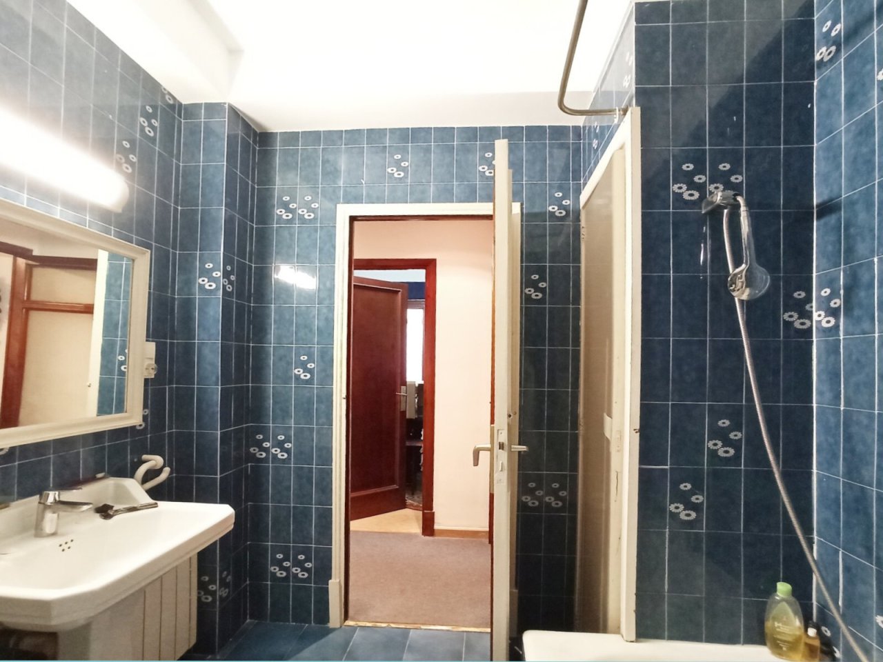 Baño moderno con ducha a nivel del suelo y lavabo práctico