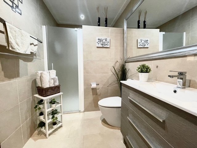 Baño moderno con pared de espejos de piso a techo y ducha a nivel del suelo