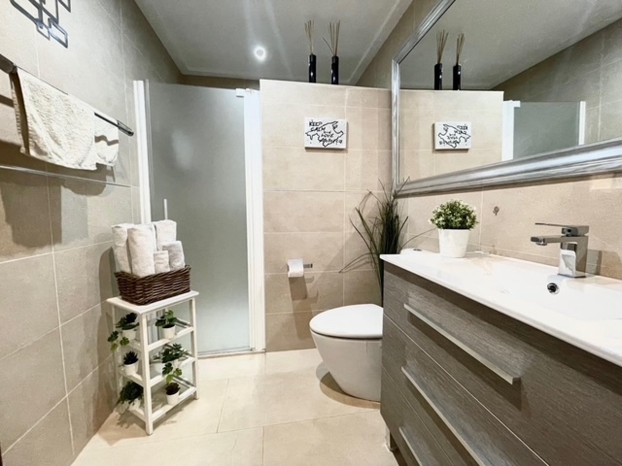 Baño moderno con pared de espejos de piso a techo y ducha a nivel del suelo