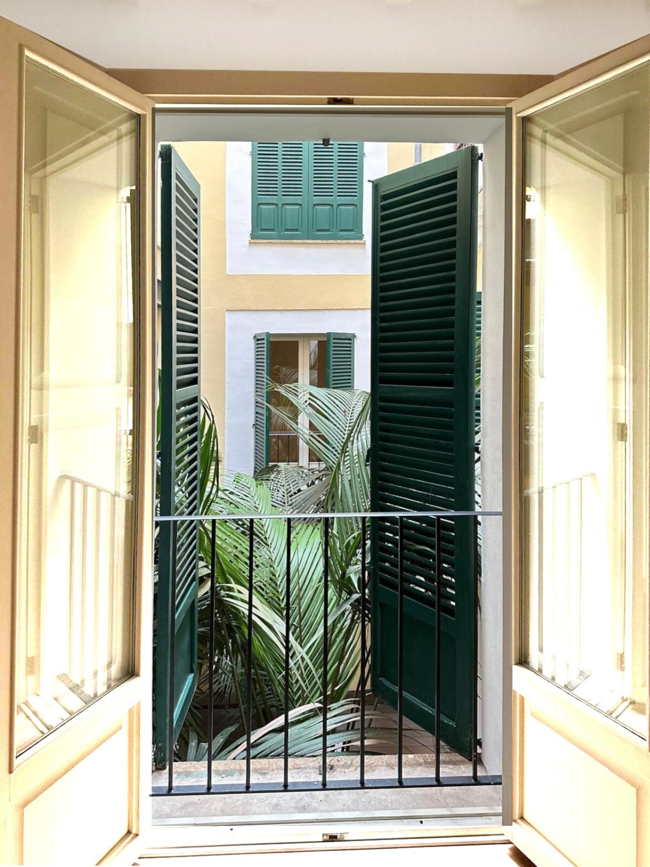 Acceso al balcón con elegantes puertas batientes y vista al patio interior