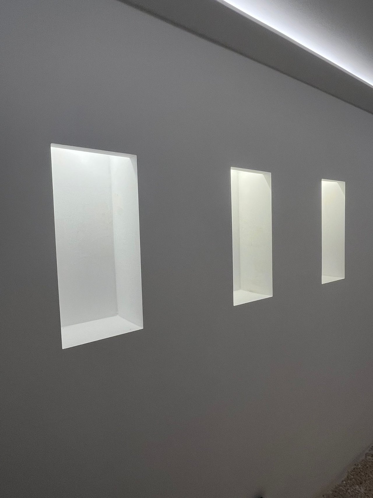 Elegantes nichos de pared con iluminación LED de acento integrada y una puesta en escena moderna del espacio Elegantes nichos de pared con iluminación LED de acento integrada y una puesta en escena moderna del espacio