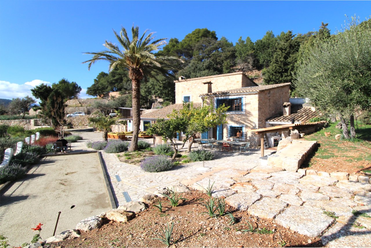 Área exterior cuidada con caminos de piedra natural, estructuras de pérgola y un diseño de jardín armonioso