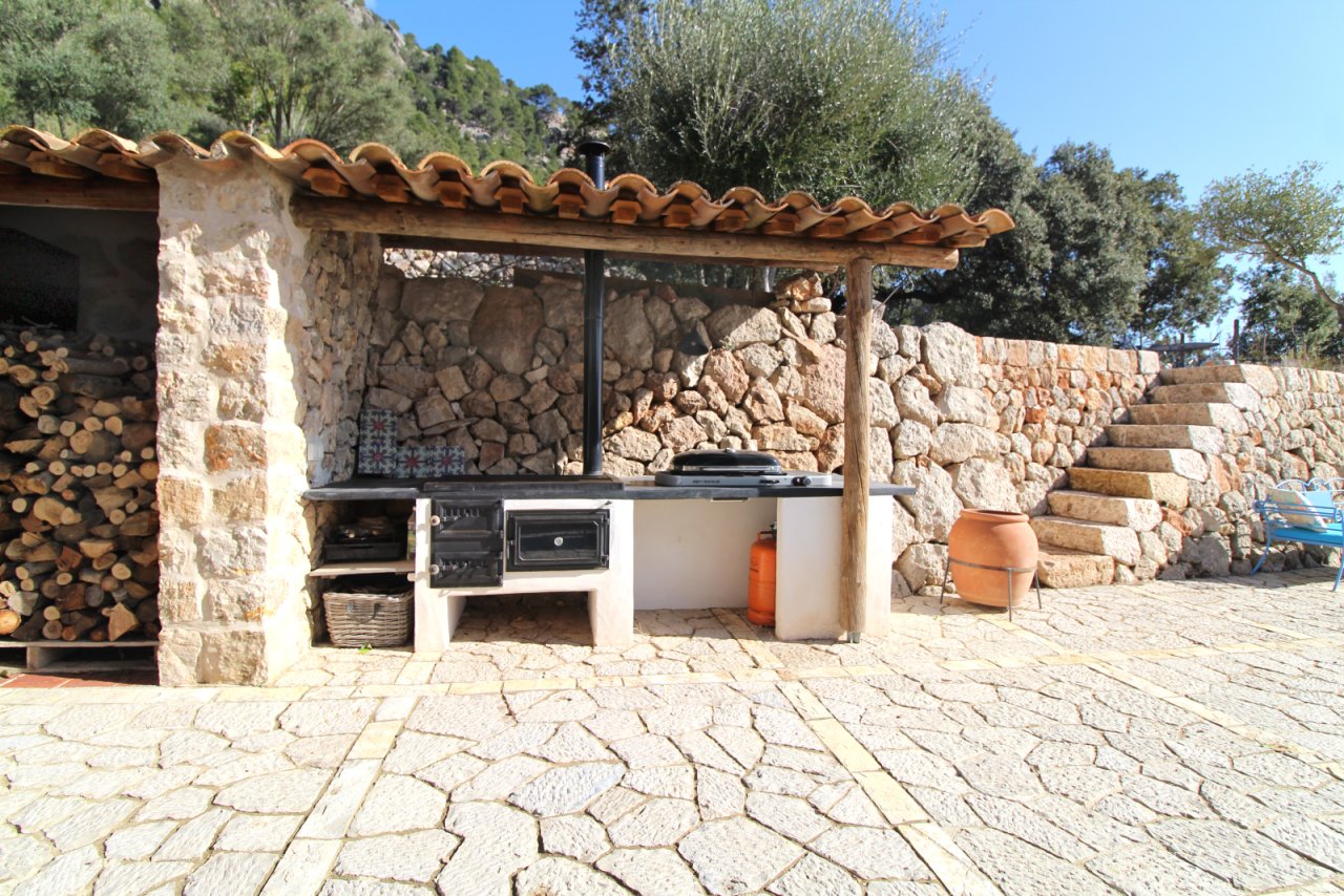 Cocina exterior con parrilla integrada y área de trabajo cubierta