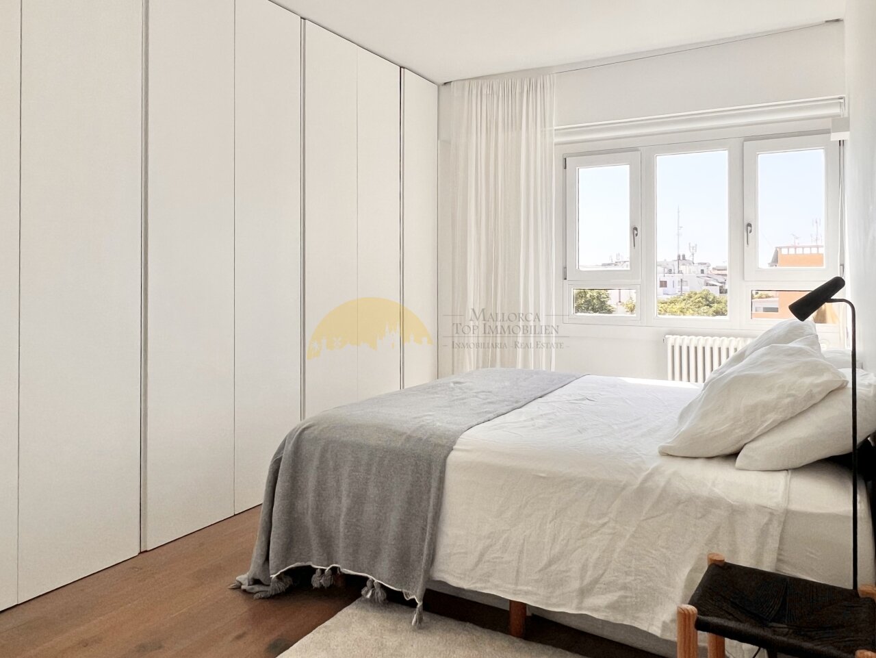 Dormitorio con armarios empotrados de suelo a techo y ventanas panorámicas con vistas a la ciudad Dormitorio con armarios empotrados de suelo a techo y ventanas panorámicas con vistas a la ciudad