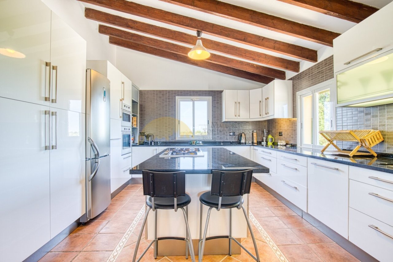 Cocina moderna con isla central, electrodomésticos de alta calidad y vigas de techo con carácter Cocina moderna con isla central, electrodomésticos de alta calidad y vigas de techo con carácter