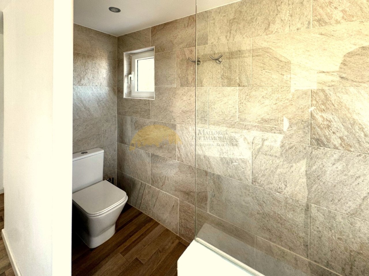 Baño moderno para invitados con ducha a nivel del suelo, revestimiento de piedra natural de alta calidad y ventana para ventilación Baño moderno para invitados con ducha a nivel del suelo, revestimiento de piedra natural de alta calidad y ventana para ventilación
