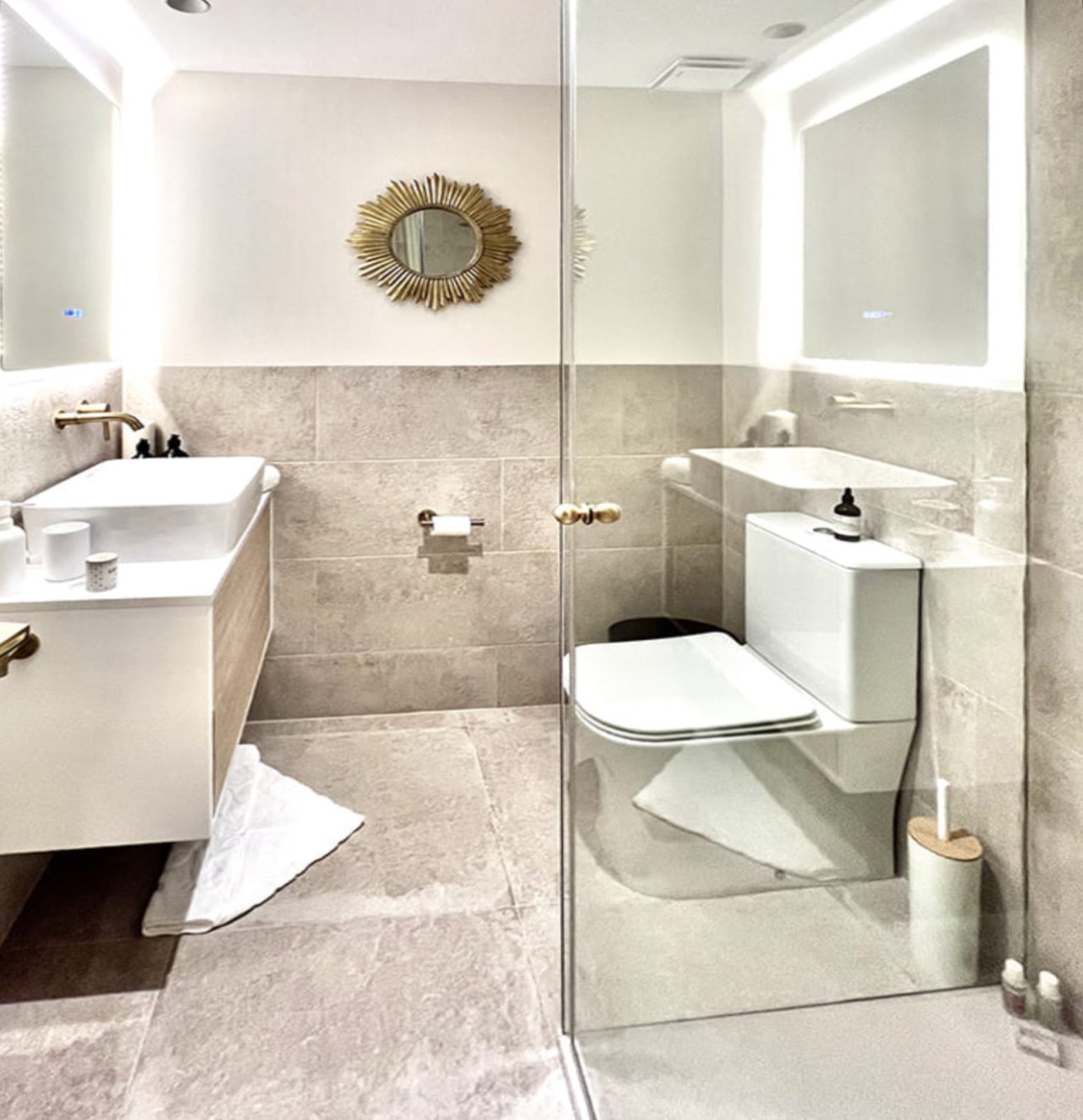 Baño elegante con ducha a ras de suelo y luces LED en el espejo Baño elegante con ducha a ras de suelo y luces LED en el espejo
