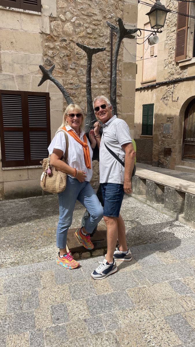 Axel und Claudia posieren vor einer Skulptur in der Altstadt von Pollença.
