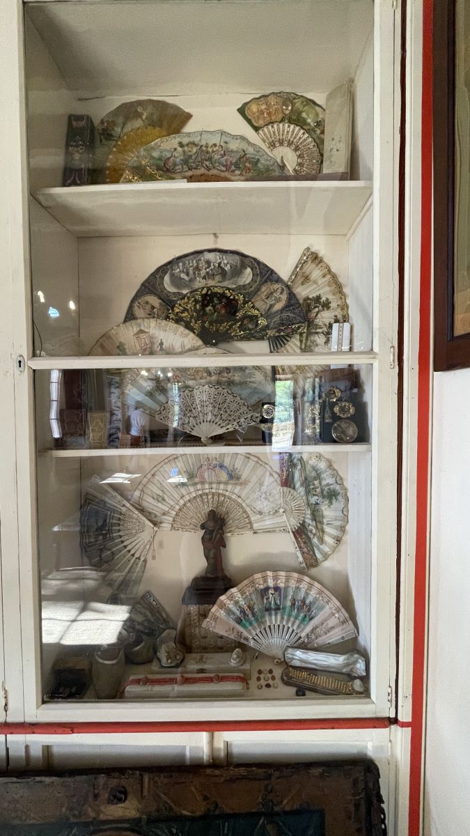 Glasschrank mit zahlreichen Fächern im Herrenhaus Els Calderers auf Mallorca, der traditionelle Artefakte zeigt.