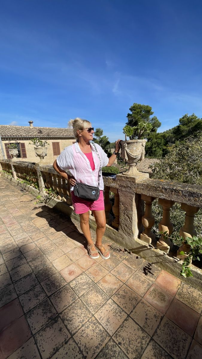 Claudia auf der historischen Terrasse des Herrenhauses Els Calderers auf Mallorca, mit Blick auf die Gärten.
