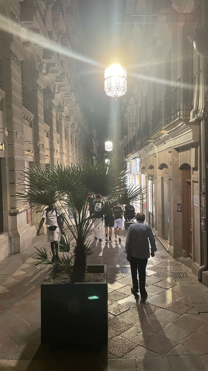 Beleuchtete Fußgängerzone in Granada bei Nacht mit Menschen und offenen Cafés