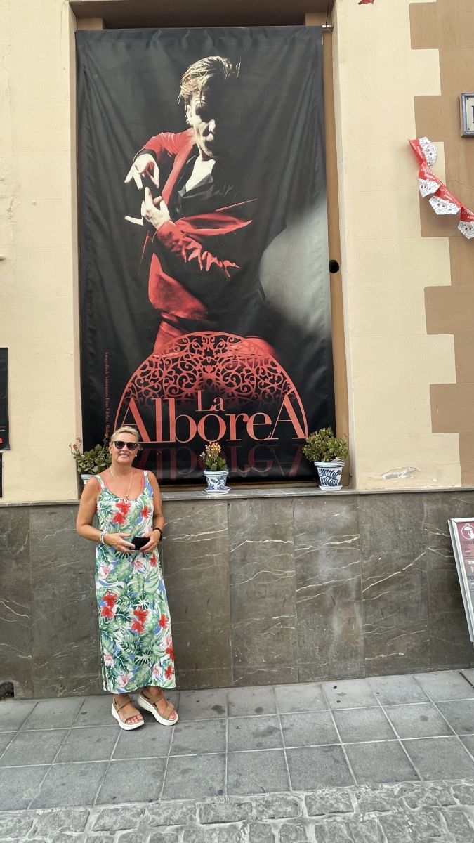 Flamenco-Tänzerin in rotem Kleid mit ausdrucksstarker Bewegung auf dunkler Bühne