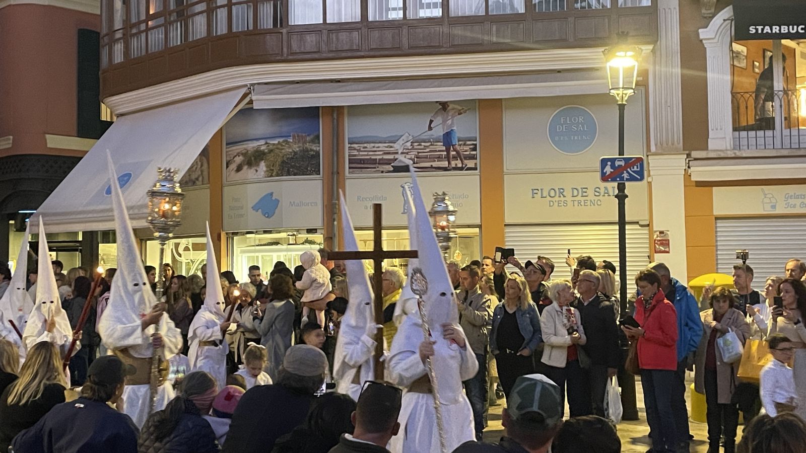 Holy Week brotherhood member lighting a candle on the procession path