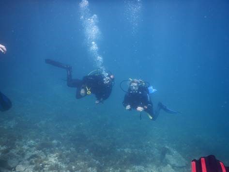 Claudia und Axel beim Abtauchen in das klare, türkisblaue Wasser vor der Küste Mallorcas im Oktober, mit Tauchmasken und Ausrüstung, umgeben von sanften Lichtstrahlen unter Wasser.