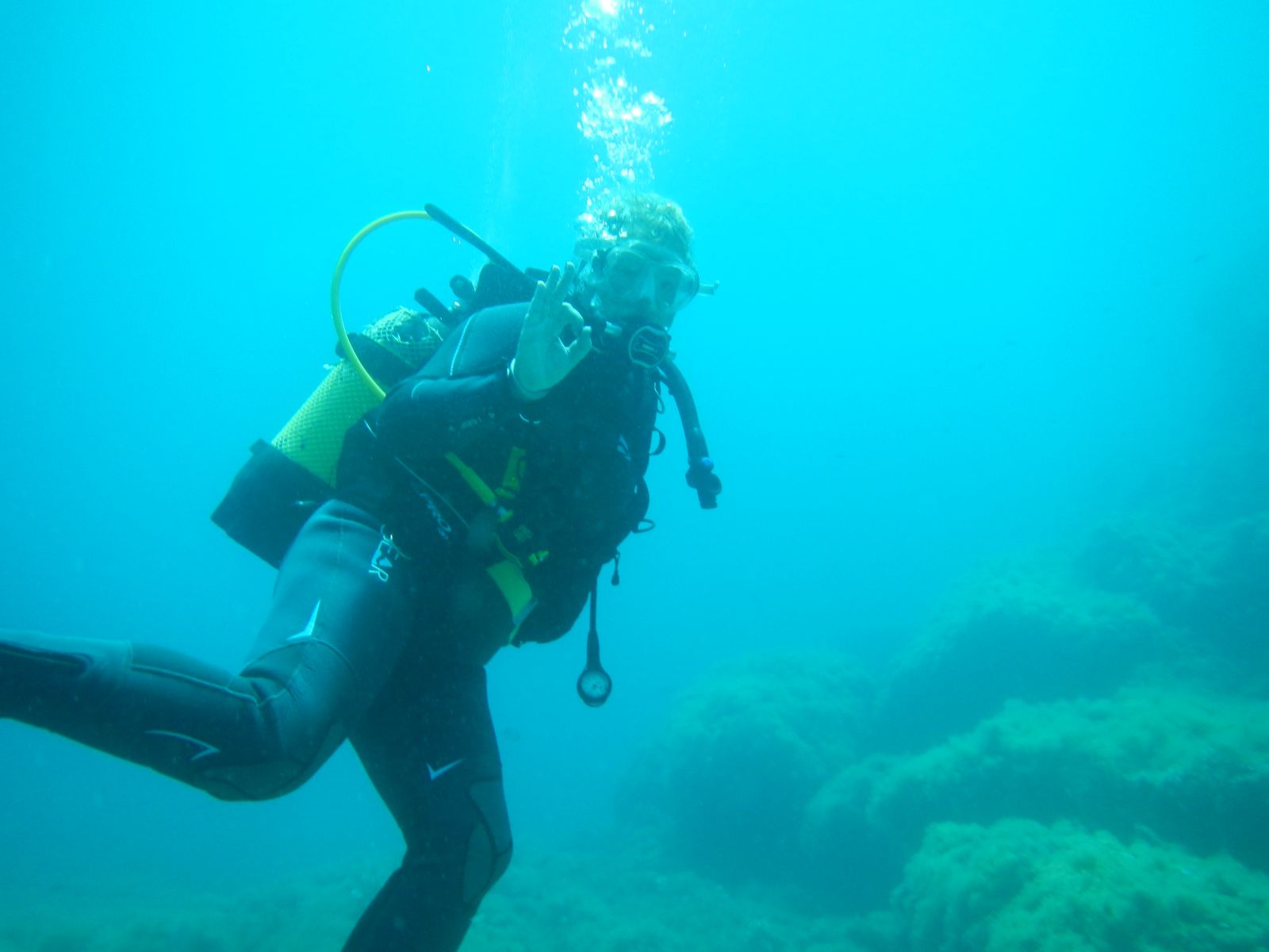 Zwei Taucher (Claudia und Axel) unter Wasser in der Nähe eines Riffs auf Mallorca, umgeben von kleinen Fischschwärmen und farbenfrohen Korallenformationen – aufgenommen bei idealem Wetter im Oktober.