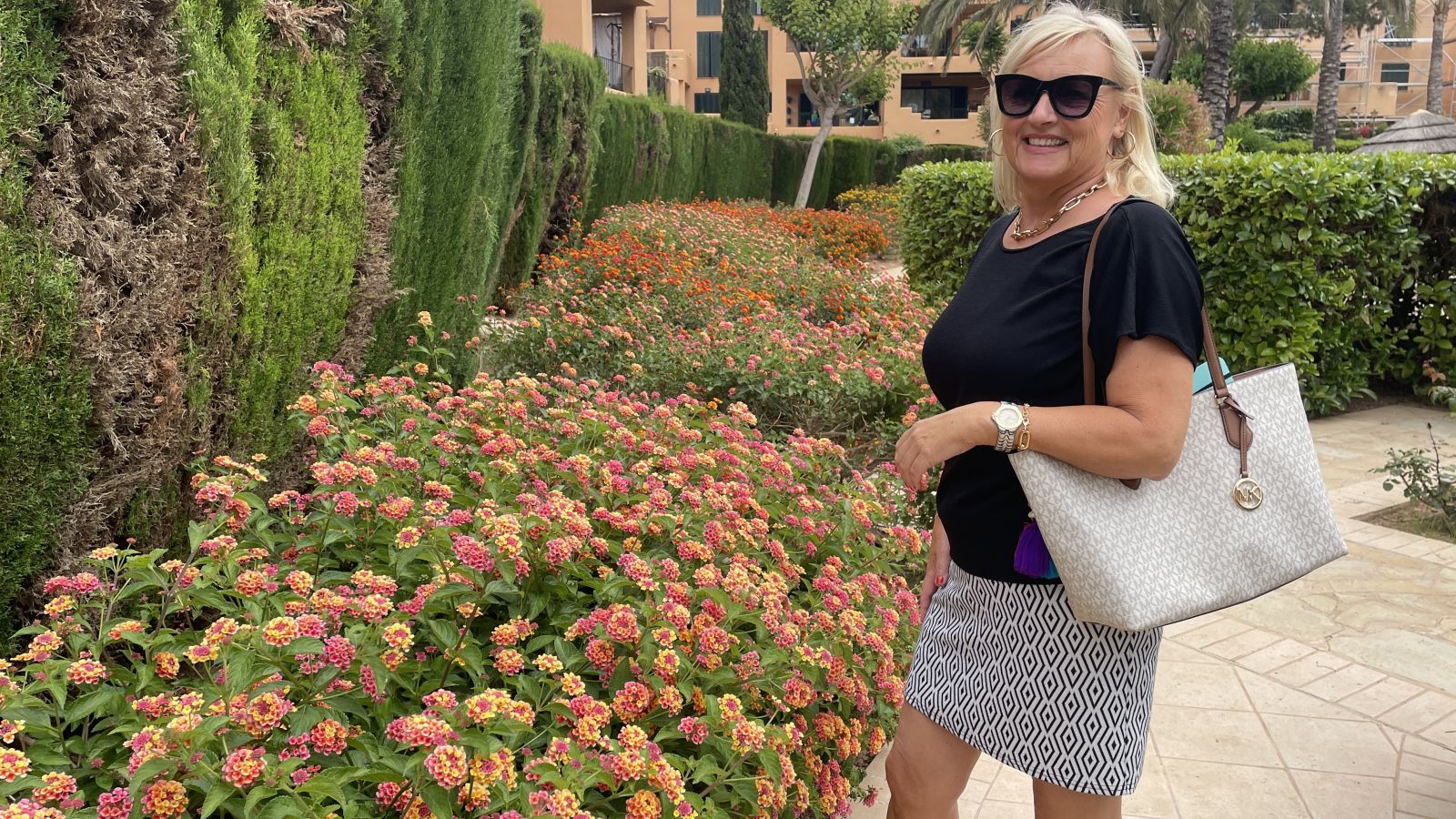„Zwei Personen stehen entspannt vor einem historischen Gebäude auf Mallorca an einem sonnigen Oktobertag. Im Hintergrund leuchtet der blaue Himmel – das milde Wetter im Herbst lädt zum Entdecken der Insel ein.“