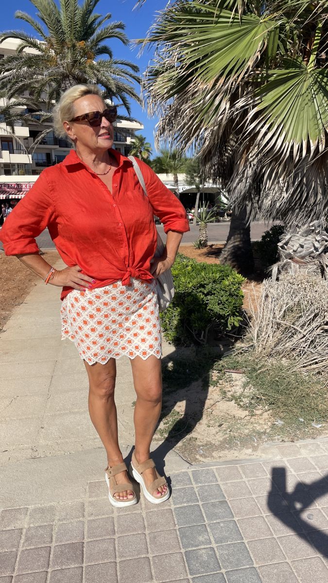 Claudia entspannt unter einer schattigen Palme an der Küste Mallorcas, umgeben von mediterraner Natur.