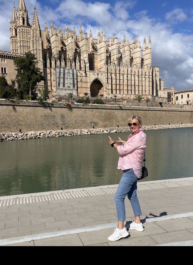 Claudia steht vor der imposanten Kathedrale von Palma de Mallorca und bewundert die Architektur.